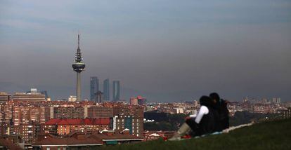 A couple look out at a smog-stained Madrid skyline.