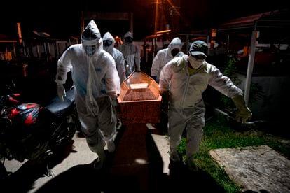 Gravediggers carry the coffin of a victim of the coronavirus for its burial in Breves in the Brazilian state of Para.