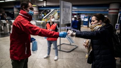 A Red Cross member hands out face masks in Atocha train station in Madrid.