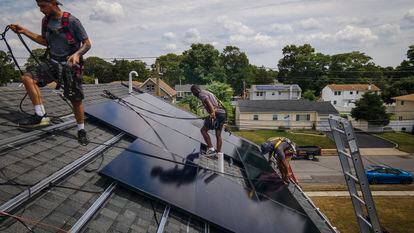 Employees of NY State Solar, a residential and commercial photovoltaic systems company, install solar panels on a roof, in August 2022, in Massapequa, New York.