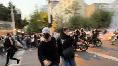 Two women flee from police during a protest in Tehran on September 20, 2022, following the death of Masha Amini.