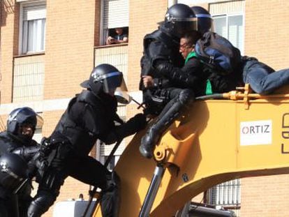 Police clash with residents who climbed on to the digger that demolished the building.