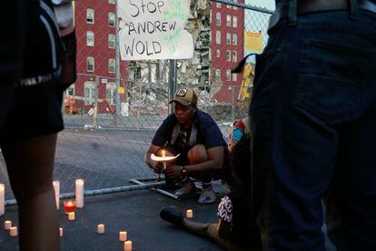 Raquel Sipp kneels with a candle at the scene of where an apartment building partially collapsed two days earlier, in Davenport, Iowa