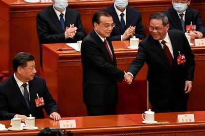 China's former Premier Li Keqiang (C) shakes hands with newly elected Premier Li Qiang (R) as China's President Xi Jinping (L) looks on during the fourth plenary session of the National People's Congress (NPC) at the Great Hall of the People in Beijing on March 11, 2023.