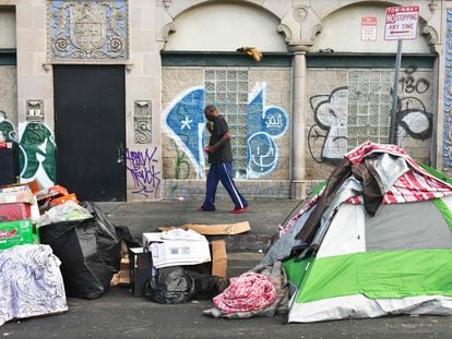 A man walks past tents housing the homeless on the streets in the Skid Row community of Los Angeles, California on April 26, 2021.