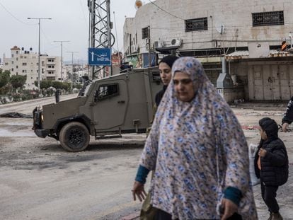 Several Palestinians walk past an Israeli military vehicle in Tulkarem, in the occupied West Bank, on Wednesday.