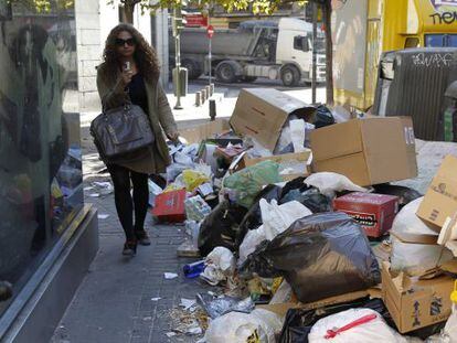 A woman walks past garbage piled up in Madrid&#039;s Amaniel street on Monday.