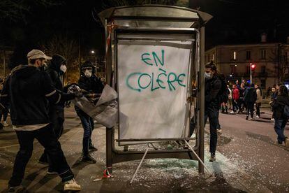 Protesters remove an advertising poster from a damaged bus shelter which reads as "angry", during a demonstration in Dijon, central France, on March 20, 2023.