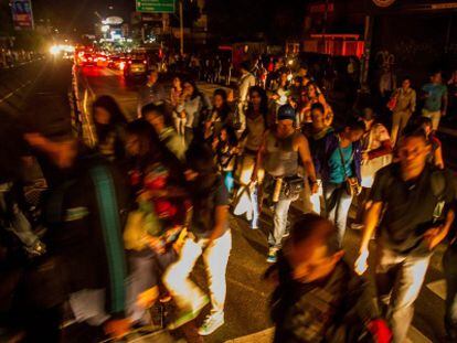 Residents walk the streets of Caracas following Monday's night blackout.