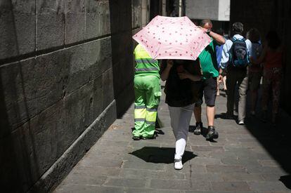 A woman in Barcelona uses an umbrella to protect herself from the sun.
