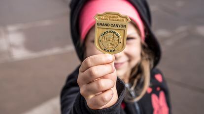 A girl proudly displays the Junior Ranger badge she received at the Grand Canyon National Park.