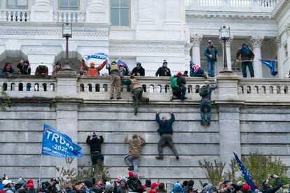 Rioting supporters of President Donald Trump climb the west wall of the the US Capitol in Washington.