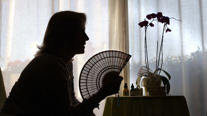 A woman uses a fan to relieve the hot flashes of menopause.
