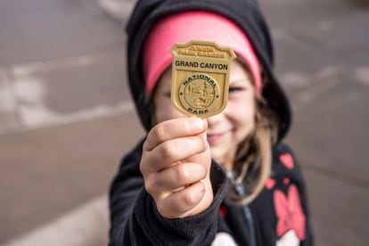 A girl proudly displays the Junior Ranger badge she received at the Grand Canyon National Park.