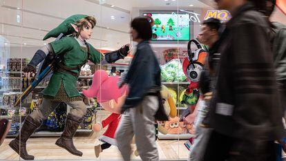 Passersby walk past a shop window in Tokyo displaying advertisements for the new 'Zelda' video game.