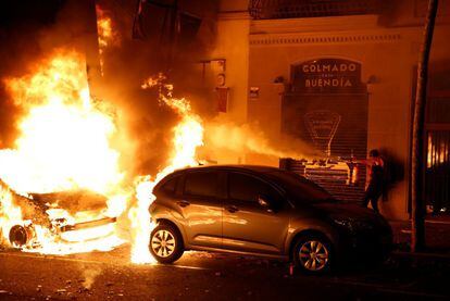 A person tries to extinguish a burning car, on the third consecutive day of protests against the Supreme Court ruling.