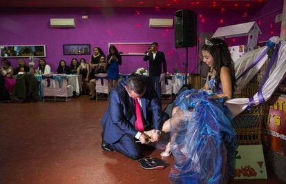 Bernardo Zapata helps his daughter Aleja into high-heeled sandals at her quinceañera party in Madrid.