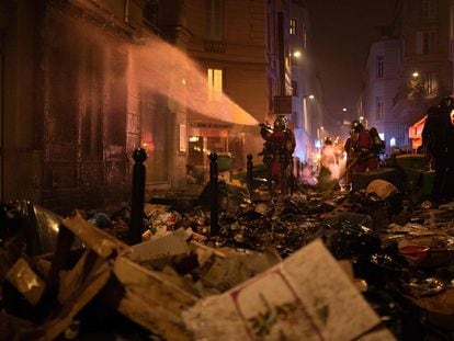 Firefighters water a facade after extinguishing a fire of rubbish during a demonstration in Paris on March 23, 2023.