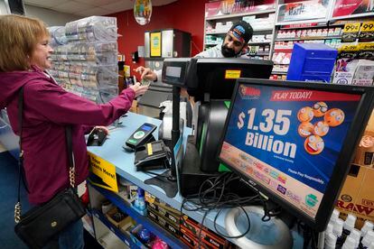 A Mega Millions sign displays the estimated jackpot of $1.35 billion as a customer purchases a Mega Millions ticket at the Cranberry Super Mini Mart in Cranberry, Pa., Thursday, Jan. 12, 2023.