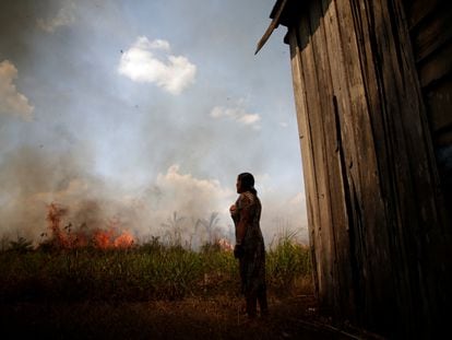 A woman watches as a forest fire approaches her home, in Porto Velho, Brazil, in August of 2020