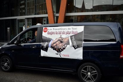 A sign reading "Taxi workers against the law of the strongest" hangs on the side of a taxi during a protest at Schuman Square in Brussels (Belgium), in 2015.