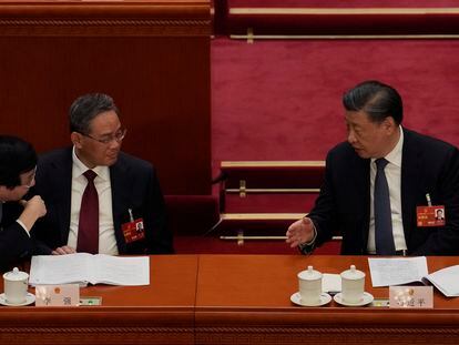 Chinese President Xi Jinping, right, speaks to Politburo Standing Committee members Wang Huning, left, and Li Qiang during a session of China's National People's Congress (NPC) at the Great Hall of the People in Beijing, Tuesday, March 7, 2023.