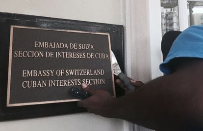 A worker removes the sign from the US Interests Section in Havana, which now functions as an official embassy.