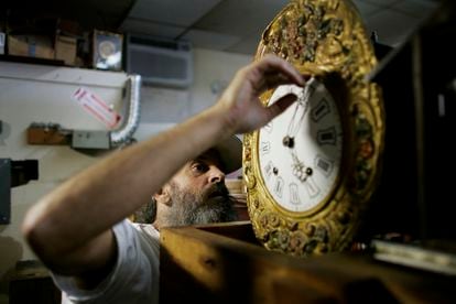 A man adjusts the time on a clock,