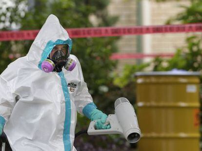 A hazmat worker cleans outside the apartment building of the infected hospital employee on Sunday.