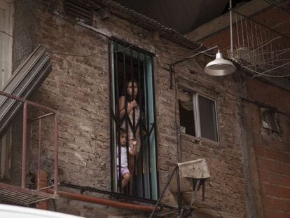 A woman and a child peer out from a doorway in Villa 31.