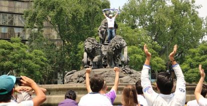 A fan of the Spanish side celebrates atop the fountain.