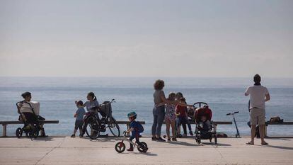 Families enjoy the seaside promenade in Barcelona.