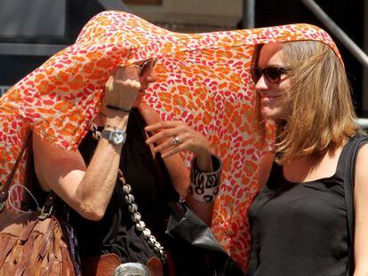 Two women try to shelter from the heat in downtown Madrid.