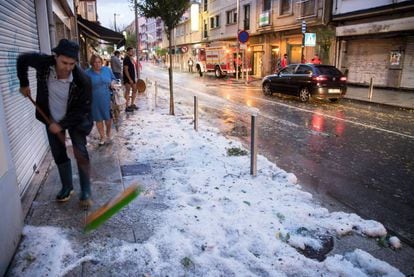 A man sweeps away hail in the center of Arzua, Galicia.