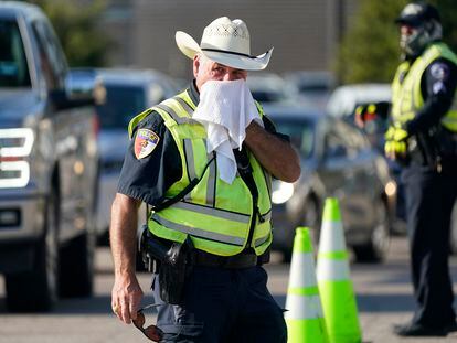 Police officer James Rhodes uses a wet towel to cool off as he directs traffic after a sporting event in Arlington, Texas, Saturday, Aug. 19, 2023.