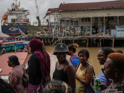People wait at Stabroek Market to cross the Demerara River by ferry, near a container ship in Georgetown, Guyana.