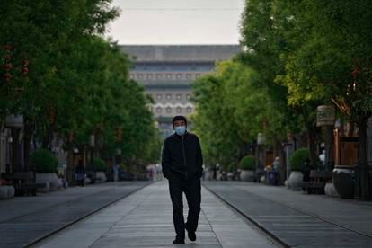 A man wearing a mask walks through the usually busy Qianmen shopping area in central Beijing.