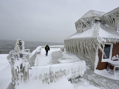 A man walks through the front yard of a house completely covered in ice floes in Buffalo, New York, on Monday.