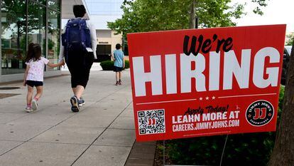 People walk past a "now hiring" sign posted outside of a restaurant in Arlington, Virginia, in June 2022.