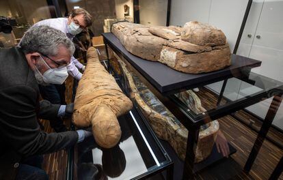 Helge Nieswandt, curator (l) and Prof. Achim Lichtenberger, Director of the Archaeology Museum at Münster University, place an elaborately restored "Münster Mummy" next to its sarcophagus in a new display case.