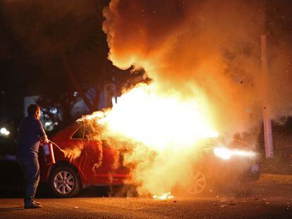 Police officers put out a burning car in Zapopan, Jalisco, on August 10.