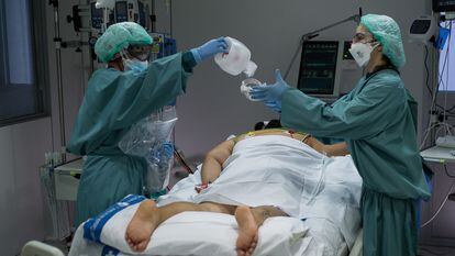 Dos enfermeras preparan a una mujer recién ingresada para su estancia en la UCI
