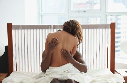 Mujer abraza a hombre encima de la cama