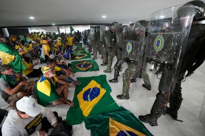 Supporters of Brazil's former President Jair Bolsonaro, sit in front of police inside the Planalto Palace after storming it, in Brasilia, January 8, 2023.