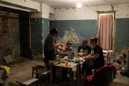 Neighbors in an apartment block have dinner together in the basement, where they take refuge at night.