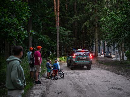 A group of people observe the fence on the border between Poland and Belarus, in the town of  Białowieża, in July of 2023