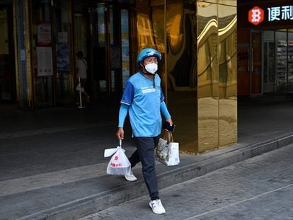 A delivery worker carries a take-away food order outside a mall in Beijing on June 20, 2022.