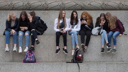 Teenagers use their phones in London, in May 2019.