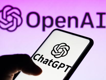 The ChatGPT logo is seen displayed on a smartphone and the OpenAI company logo on the background.