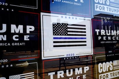 A "Thin Blue Line" sign is surrounded by other signs supporting then-president Donald Trump on the windows of the Racine County Republican Party Office in Racine, Wisconsin, in 2020.